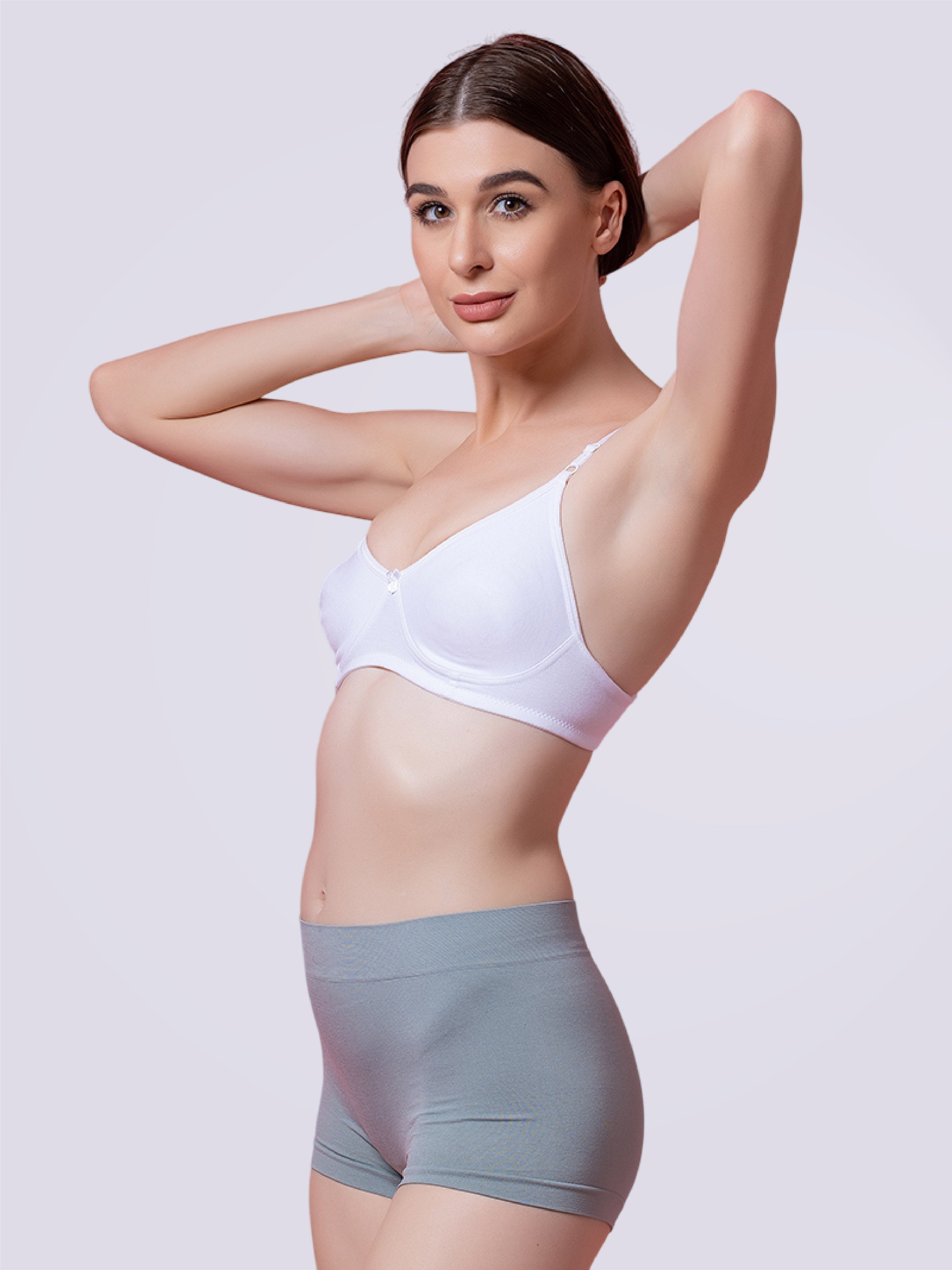 Woman wearing a white bra and gray shorts on a plain background